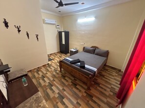 A hotel room with a bed, a desk, a wardrobe, and a ceiling fan. - Le'SAP Beach Resort (Vanur)