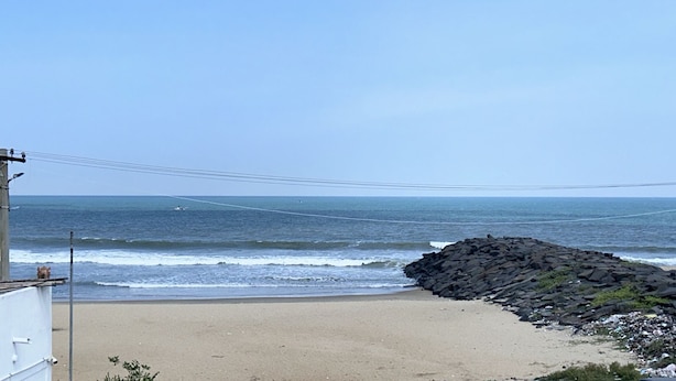 Une plage dotée d’une digue rocheuse et offrant une vue dégagée sur l’océan.