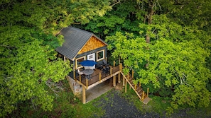 Une cabane en bois dotée d’une terrasse, entourée d’une forêt dense.
