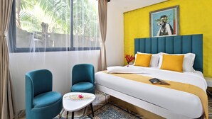 A hotel room with a bed, two chairs, a small table, and a window with curtains. - Royale Amata By the Beach (Morjim)