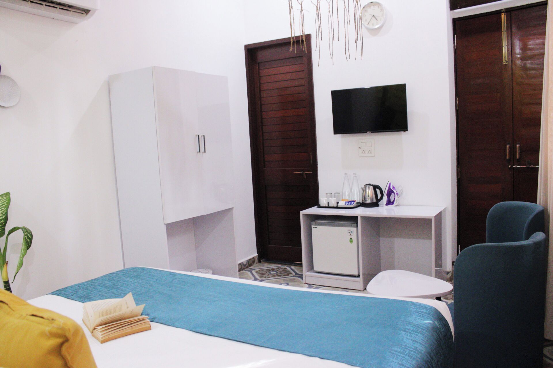 A hotel room with a bed, a desk with a computer, a TV, and a wardrobe.