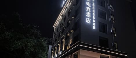 Un immeuble d’hôtel à plusieurs étages, doté d’une enseigne lumineuse et d’une entrée bien visible.