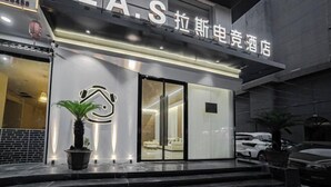 Ingresso di un hotel dal design moderno, con un evidente cartello 'LAS' e un interno ben visibile, che include una poltrona e una pianta.