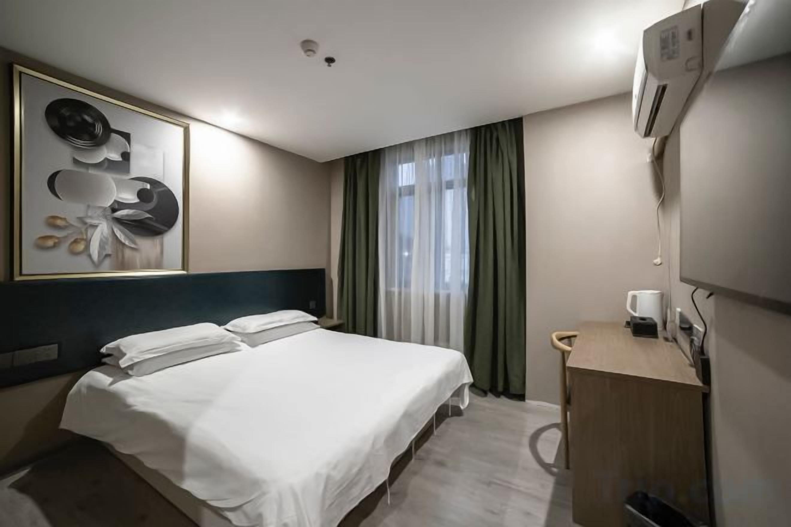 Une chambre d’hôtel avec un lit, un bureau, un miroir et une fenêtre avec des rideaux.