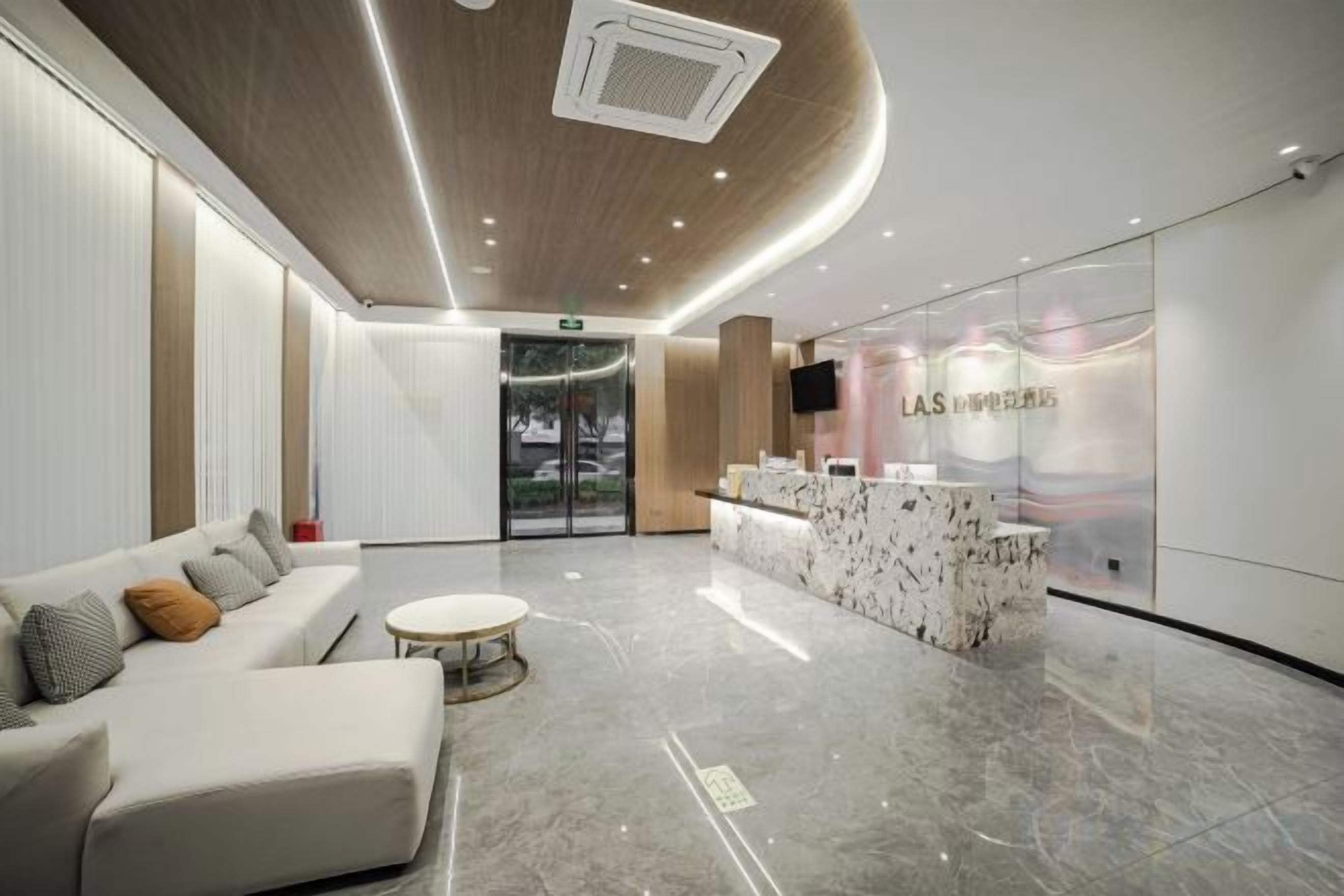 A modern reception area with a marble floor, a reception desk, a sofa, and a television screen.