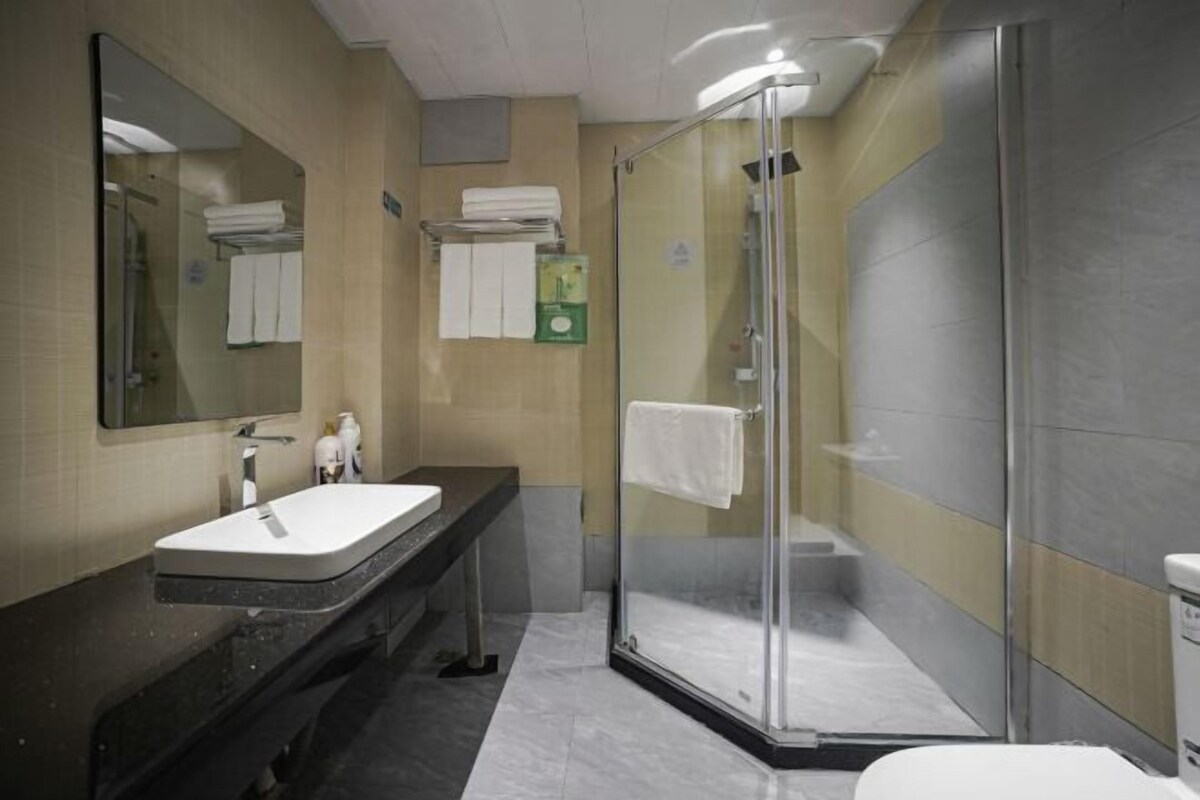 A modern bathroom with a glass-enclosed shower, a sink with a mirror, and a towel rack.