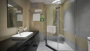 Un baño moderno con ducha de vidrio, lavabo con espejo y toallero.