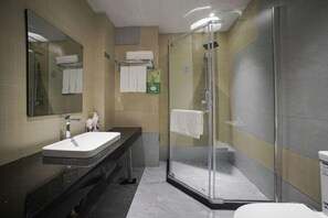 A modern bathroom with a glass-enclosed shower, a sink with a mirror, and a towel rack.