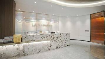 A reception area with a marble counter, glass display, and a wooden panel on the left.
