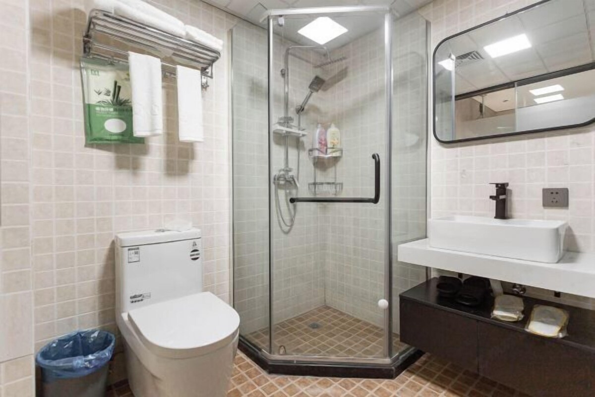 A bathroom with a glass-enclosed shower, a toilet, a sink, and a mirror.