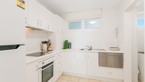 A compact kitchen with white cabinets, a built-in oven, a dishwasher, and a window above the sink. - Rainbow Pacific Unit 4 - Oceanfront Unit in Rainbow Bay, Coolangatta Linen and Wi-Fi included (Coolangatta)