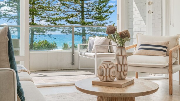A modern living room with a view of the sea, a round wooden table, and two decorative vases. - Rainbow Pacific Unit 4 - Oceanfront Unit in Rainbow Bay, Coolangatta Linen and Wi-Fi included (Coolangatta)