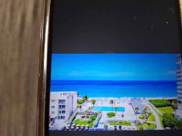A view of a hotel with a pool, a clear blue sky, and the ocean in the background.