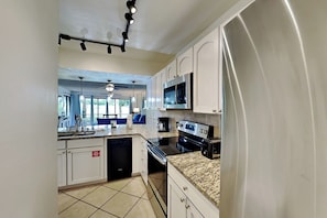 A kitchen with white cabinets, a microwave, a stove, and a dishwasher.