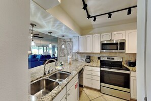 A modern kitchen with stainless steel appliances, a granite countertop, and a coffee station.