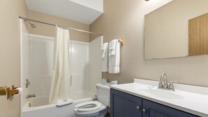 A modern bathroom with a bathtub, toilet, and sink. - Commander Motel (Pequot Lakes)