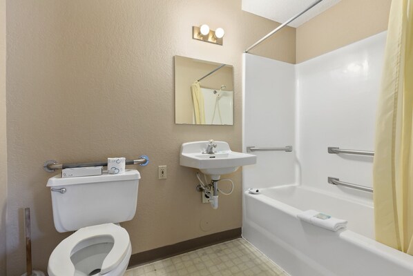 A bathroom with a toilet, sink, mirror, and bathtub.