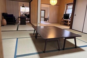 A traditional Japanese room with tatami flooring, a low table, a sofa, and a television. - Kyoto Osaka Sumireya (Takatsuki)