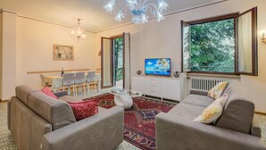A modern living room with a sofa set, a glass coffee table, a chandelier, and a television. - Villa Alberti 900m From Garda Lake (Salò)
