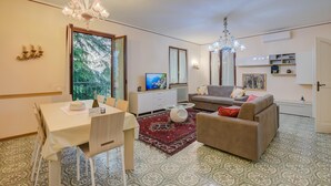 A living room with a dining table, sofa, and TV. - Villa Alberti 900m From Garda Lake (Salò)