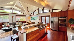 A spacious kitchen with wooden cabinets, a central island, and a built-in oven. - Short Walk to Beach Hanalei Bay (Hanalei)