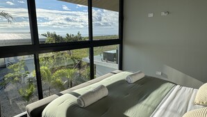 Une chambre dotée d’une grande fenêtre, d’un lit avec une serviette, et offrant une vue sur le paysage.