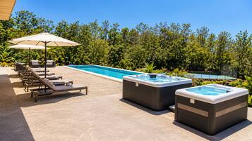 A pool area with lounge chairs, a hot tub, and a covered seating area.