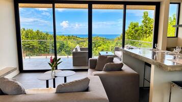 A modern living space with a balcony, a sofa, a small table, and a bar area with glasses.