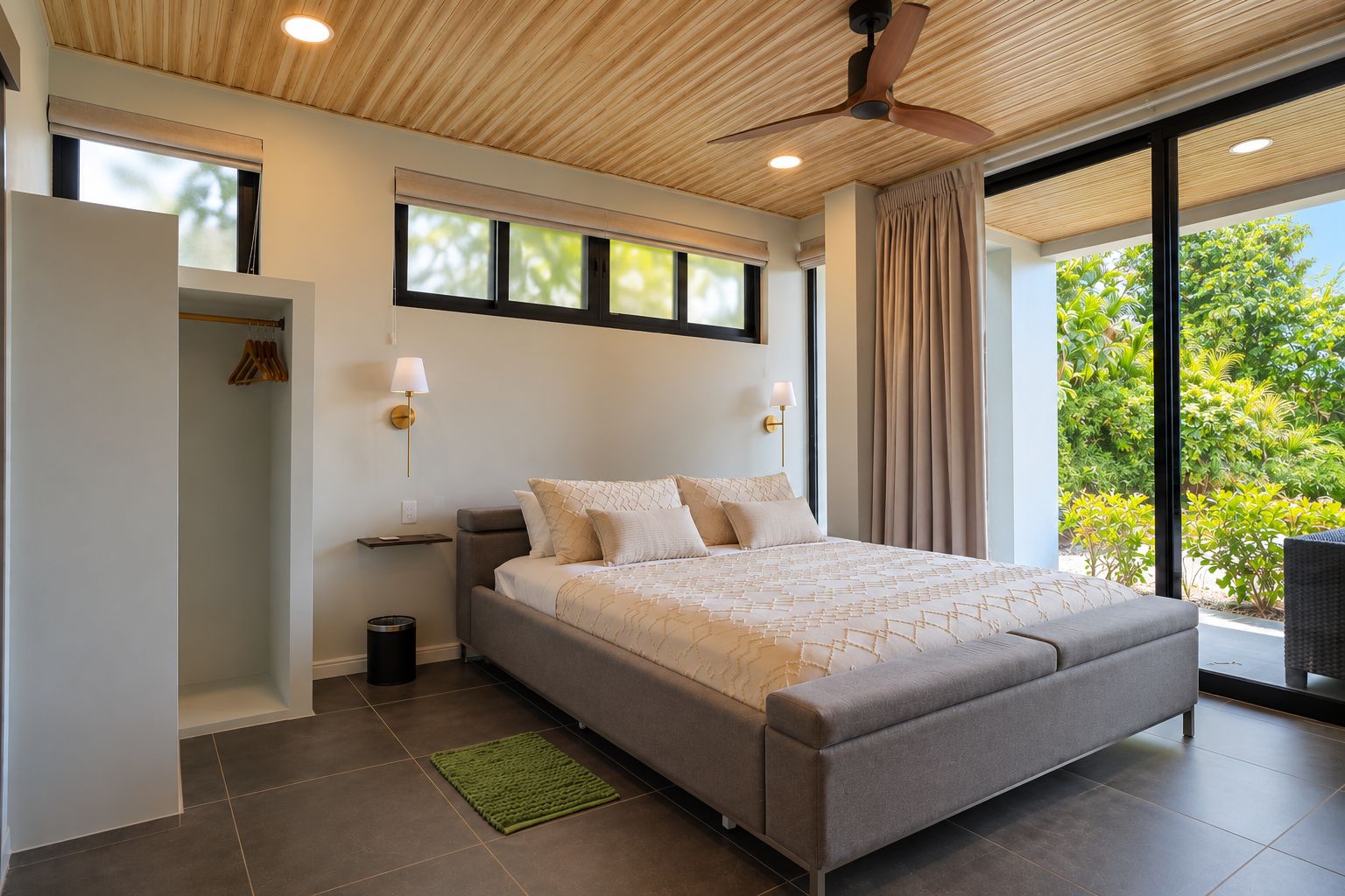 Un dormitorio moderno con una cama grande, un ventilador de techo y vistas a zonas verdes.