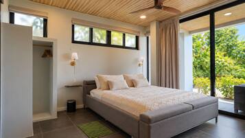Un dormitorio moderno con una cama grande, un ventilador de techo y vistas a zonas verdes.