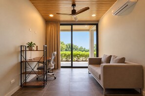 A modern living room with a sofa, a desk with a chair, and a ceiling fan.