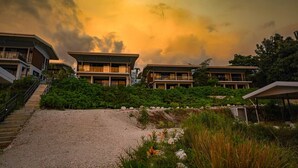 Un resort moderno con varias edificaciones de dos pisos, un camino de grava que lleva a la entrada y exuberante vegetación alrededor de la propiedad.