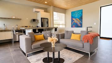A modern living room with a grey sofa, a round coffee table, and a painting of a turtle on the wall.