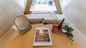 A cozy room with a bed, a mirror, a welcome sign, and a small plant. - New A-Frame Tiny Home Retreat -With Private Sauna! (Christiana)
