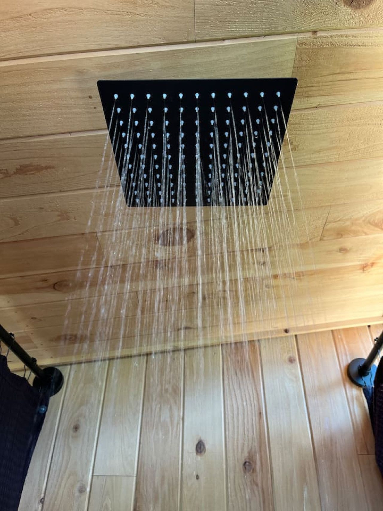 A showerhead with multiple nozzles, wooden floor, and a wooden ceiling.