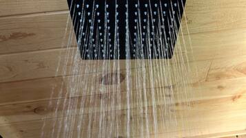 A showerhead with multiple nozzles, wooden floor, and a wooden ceiling.