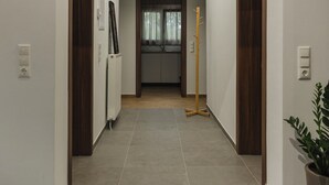 Un pasillo con piso de madera, paredes blancas y una lámpara en el techo.