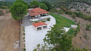Una casa con techo de tejas rojas, rodeada de follaje y un paisaje montañoso.