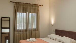 Un dormitorio con cama, mesita de noche, espejo y ventana con cortinas.