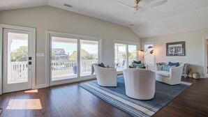 Un salon spacieux avec un plafond haut, de grandes fenêtres et une vue sur l’extérieur.