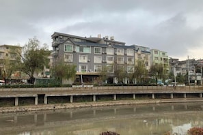 A multi-story building with a flat roof, likely a hotel or apartment complex, adjacent to a calm river.