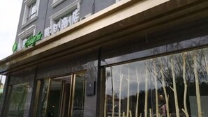 A building with large glass windows and a green sign. - Holiday Inn Express Strasbourg (Zherong)