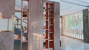 A modern interior with a large bookshelf, a polished floor, and a view of trees through a window. - Holiday Inn Express Strasbourg (Zherong)