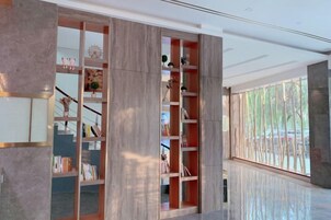 A modern interior with a large bookshelf, a staircase, and a view of the outdoors.