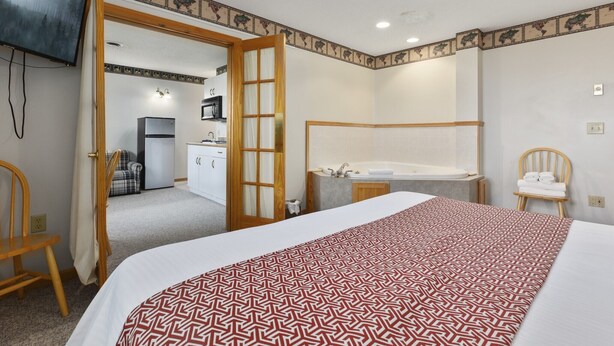 A hotel room with a bed, a bathroom with a bathtub, a desk, and a kitchenette. - Pelican Lakes Motel (Pequot Lakes)