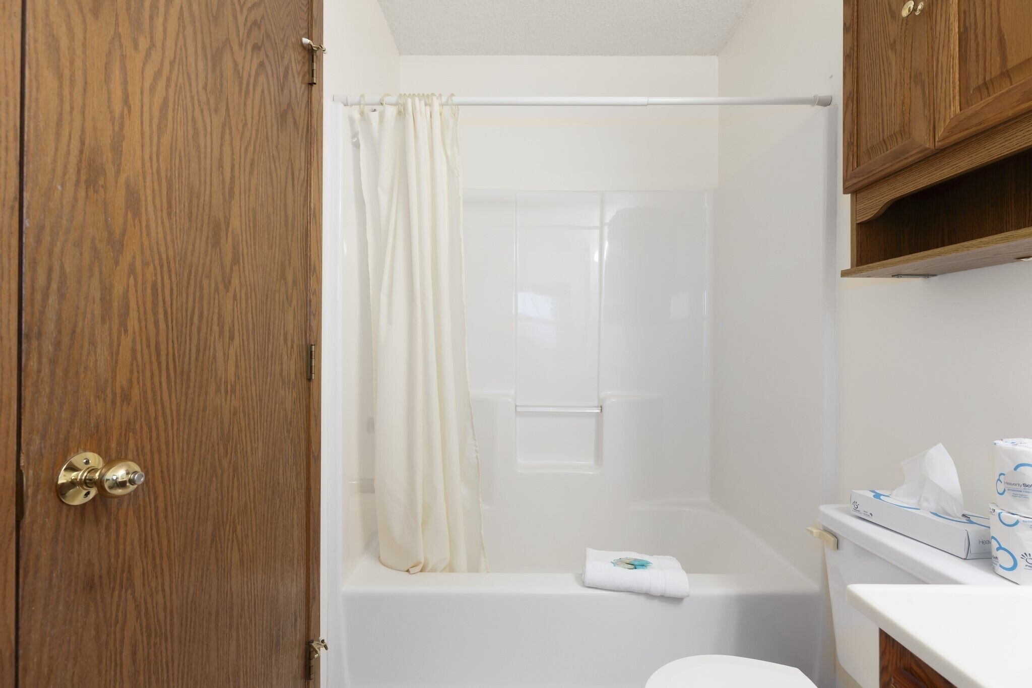 Un baño con puerta de madera, cortina de ducha, bañera y un inodoro.
