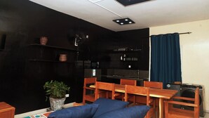 Un espacio habitable compacto con kitchenette, comedor y zona de estar con un sofá azul.