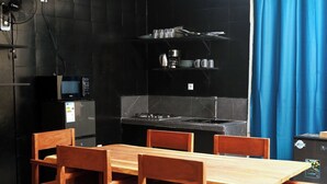 Cocina compacta con microondas, estufa y mesa de comedor de madera.
