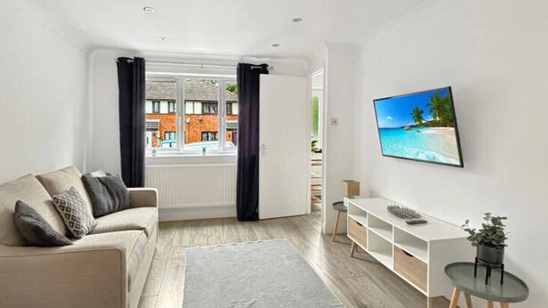 A modern living room with a sofa, TV, and a view of the outside. - 2bedroom sleeps 6 garden driveway Free Gym Access (Grantham)