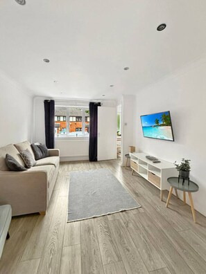 Een moderne woonkamer met een bank, televisie en uitzicht.